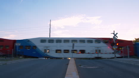 a train passes at a train stop when the gate lights are flashing and that gates are down