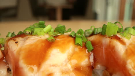 cebollino verde picado encima de rollos de sushi de salmón en un restaurante de sushi - macro