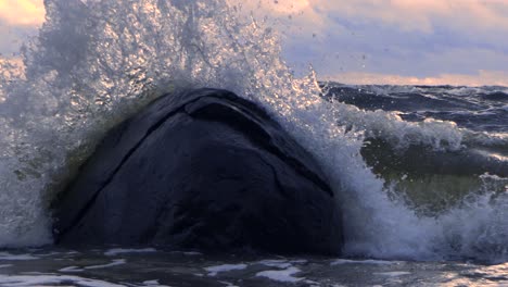 Waves-in-the-sea-during-a-thunderstorm-at-sunset,-large-stones-on-the-sea-shore