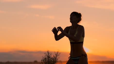 Schönes-Volleyballmädchen-Im-Bikini-Bei-Sonnenuntergang,-Unterarmpass-Mit-Ihrer-Teamkollegin-Während-Eines-Spiels