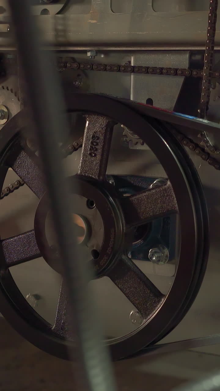 Transmission belt and rotating wheels on automatic production line closeup. Machine tool operating mechanism. Manufacturing plant technology