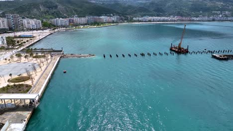 Cubierta-De-Barco-En-Construcción-En-El-Mar-Cerca-De-Un-Centro-Turístico-Con-La-Ciudad-Al-Fondo