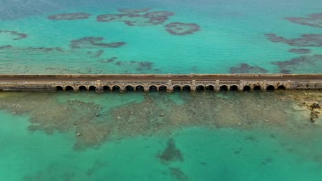 aerial view of car bridge over turquoise water on tropical island