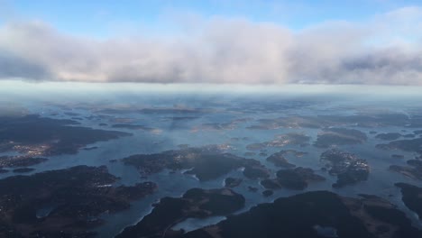 vista desde un avión que vuela sobre las islas y la ciudad a la misma altura que las nubes