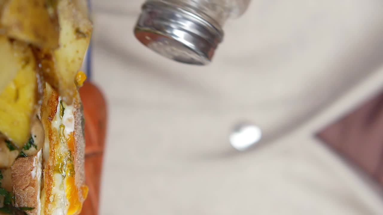 Adding seasoning to a Grilled Cheese sandwich with potatoes