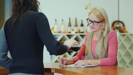 a woman tastes wine in a small winery communicates with the seller