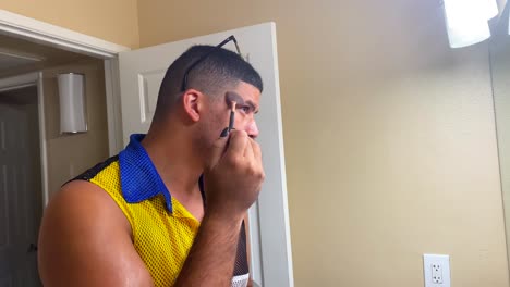 raza mixta, gay, hombre negro aplicando brillo corporal y maquillaje a su cara atractiva - concepto: diversidad, género, sexualidad, igualdad, aceptación