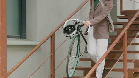 Close-Up-Of-An-Unrecognizable-Woman-In-Formal-Clothes-Carrying-Her-Bike-Down-The-Stairs