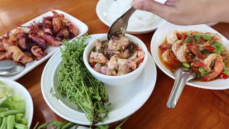 hands mixing a fresh thai seafood salad.