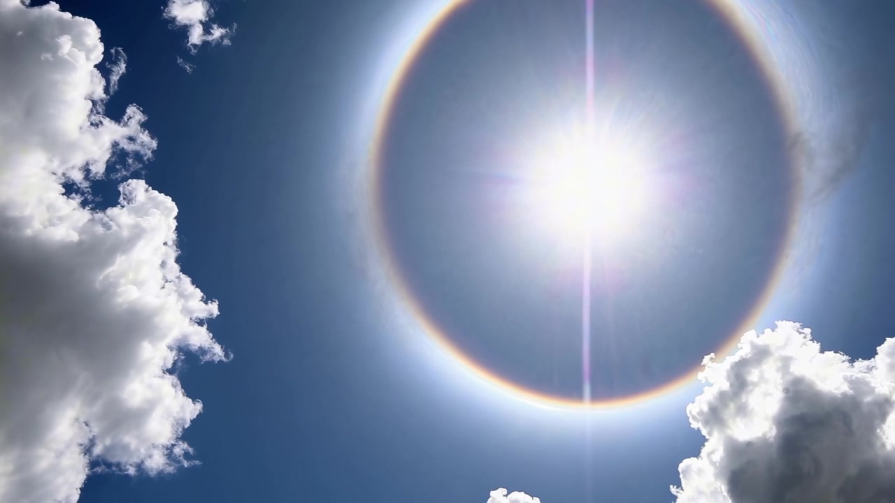 雲が浮かぶ澄み切った青空に現れる日暈
