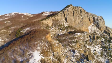 snowy mountain range with cliff face and ocean view