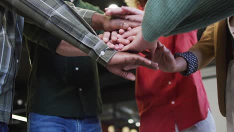 Diverse-business-people-teaming-up-with-hands-together-at-office