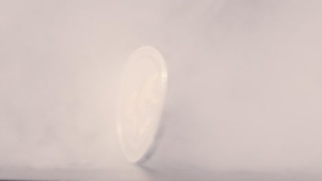 ripple coin spinning in slow motion through smoke