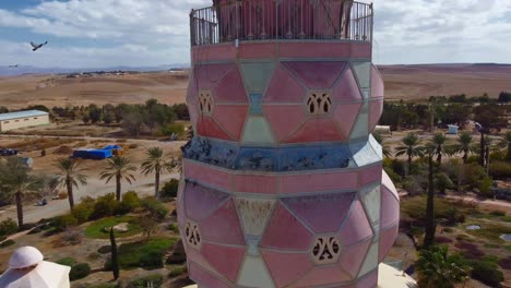 Architectural details of Neot Smadar Arts Center cooling tower with pigeons on roof, Arava desert in the background, Aerial closeup