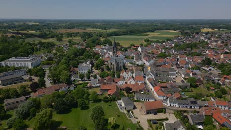 Wide-angle-drone-shot-over-the-historic-commune-of-Maasgouw,-Thorn-in-Limburg-with-beautiful-view-of-the-Limburg-Abbes-Church,-houses-and-the-flat-landscape-on-a-sunny-day