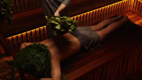 man in a sauna receiving a herbal treatment