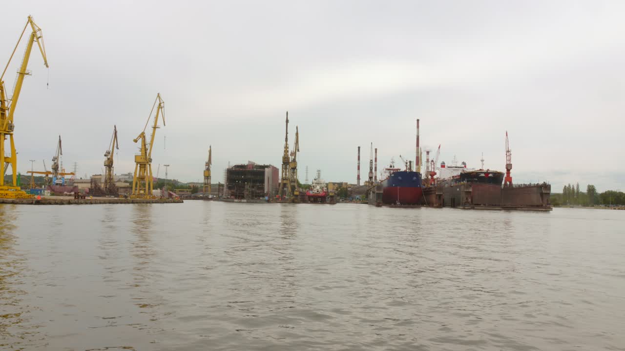 Over the water view of the industrial seaport with ships, huge cranes and depots in the city of Gdansk.