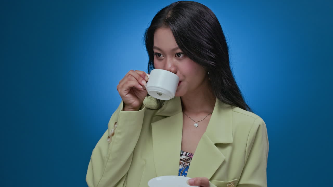 Asian Businesswoman Drinking Coffee on Neon Blue Background