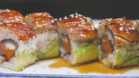 cook pouring sushi set with sauce while preparing dish in modern kitchen