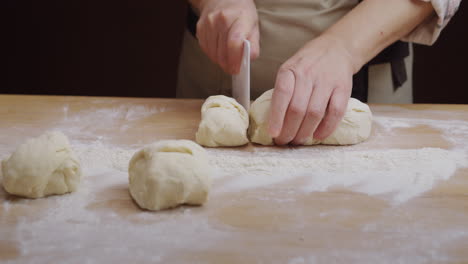 the baker rolls out the dough for buns on the board. working in a bakery