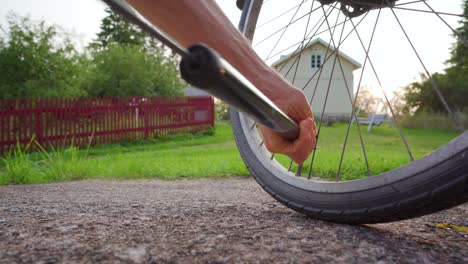 man pumping up a bicycle tire in rural environment on a sunny summer evening