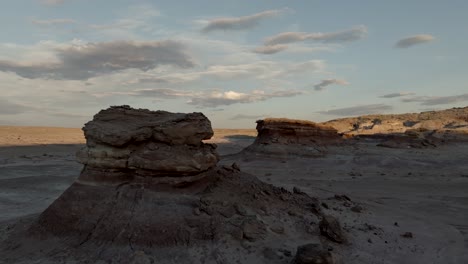 flying by a rocky desert butte in the desert at sunset