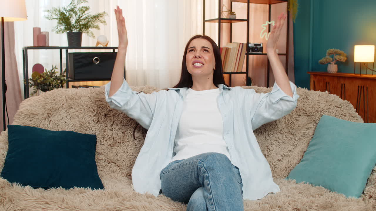 Young woman sitting on sofa stressed after bad day experiencing failure emotionally holding her head