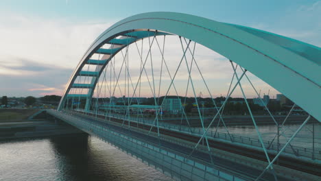 modern arch bridge over a river at sunset