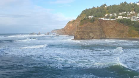 Las-Olas-Del-Océano-Llegan-A-Una-Hermosa-Playa-De-La-Costa-De-Oregon-Con-Acantilados-Al-Fondo