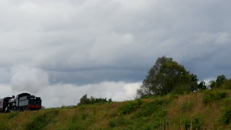 static shot of a steam train going backwards through the english countryside