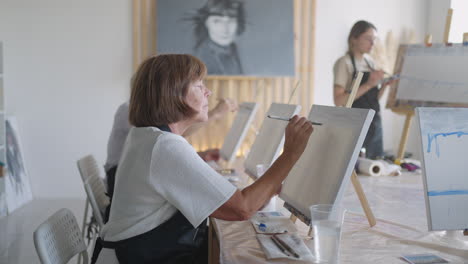 like senior friends attending together at a painting class. small group taking a variety of fun classes together. a group of elderly people attend a master class on drawing together spending time.