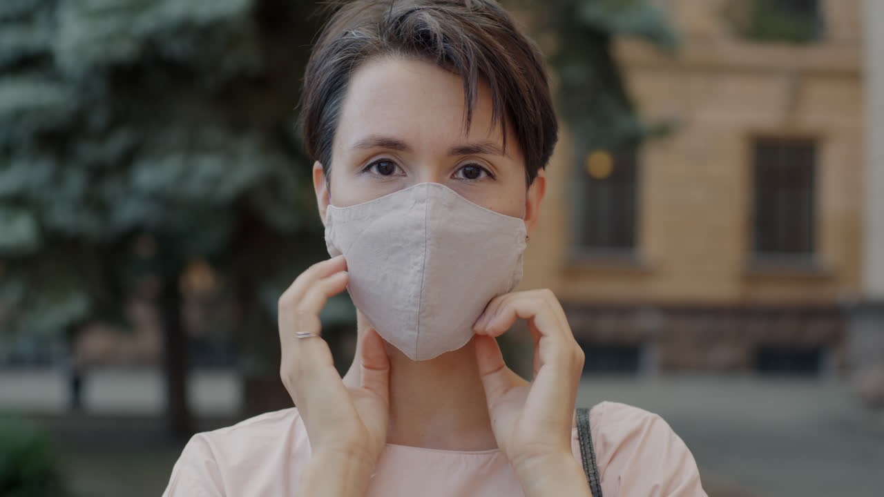 야외에서 얼굴 마스크를 조정하는 여성