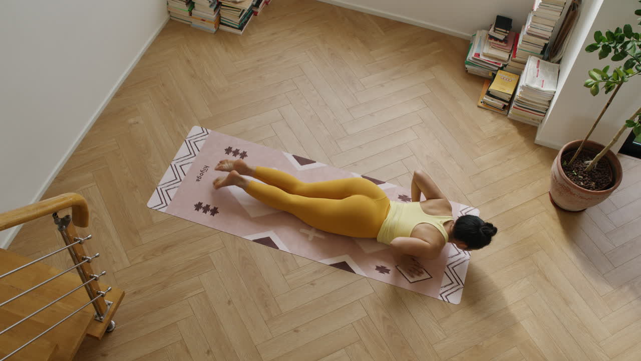 vista de arriba hacia abajo de una joven atlética en forma asiática practicando yoga san saludo en su habitación de apartamento, entrenamiento de mente y cuerpo, estilo de vida saludable