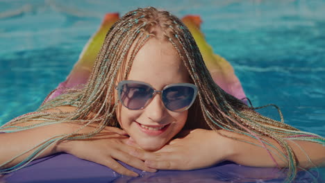 Girl-with-afro-pigtails,-swims-on-an-inflatable-mattress-in-the-pool,-resting-and-enjoying-the-rest