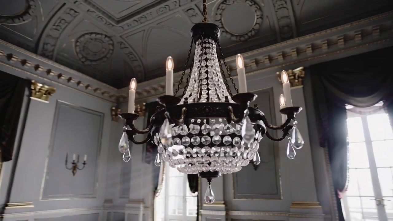 La ripresa inizia con la telecamera che si avvicina a un lampadario di cristallo in una sala di ricevimento, rivelando perle sfaccettate.