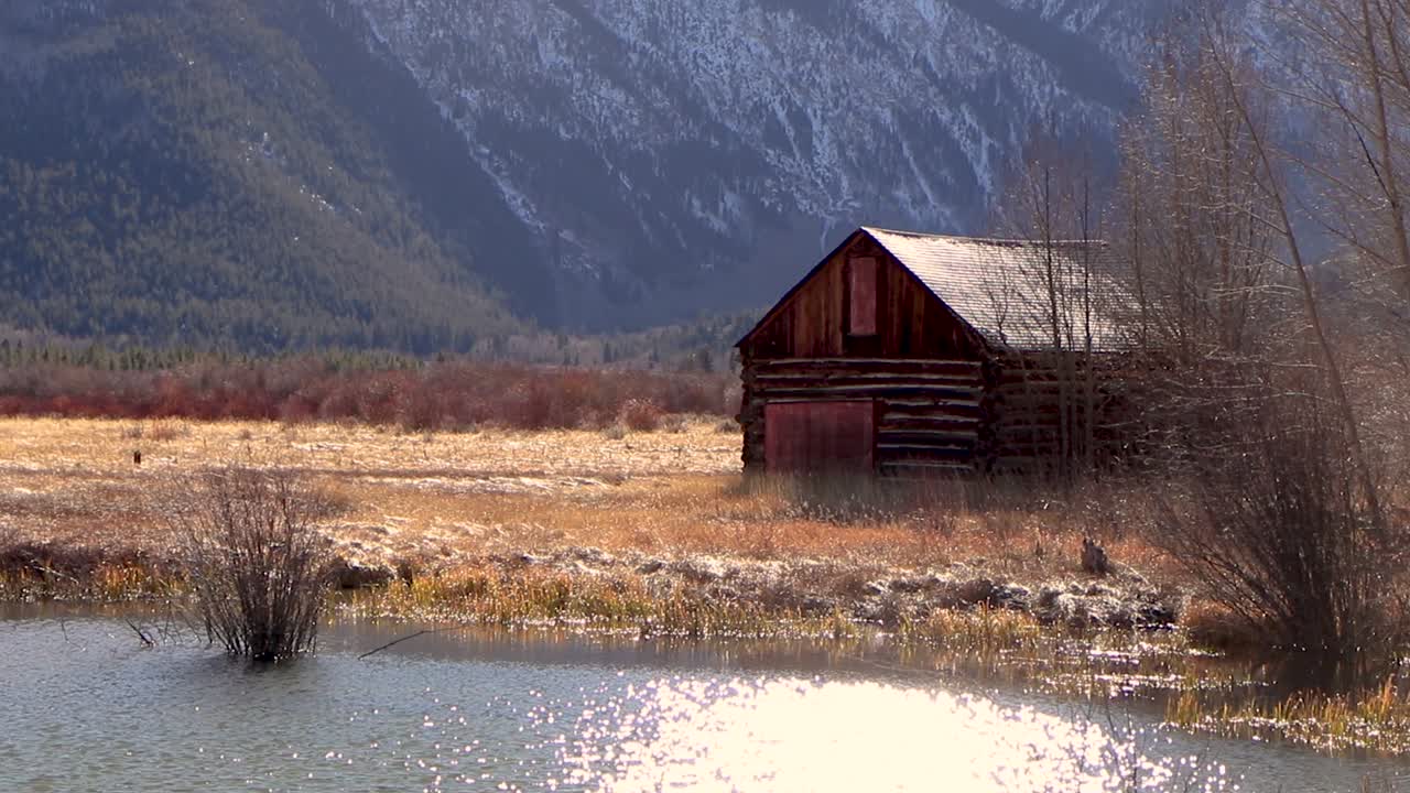 Video of a small wooden cabin near a huge snowy mountain range