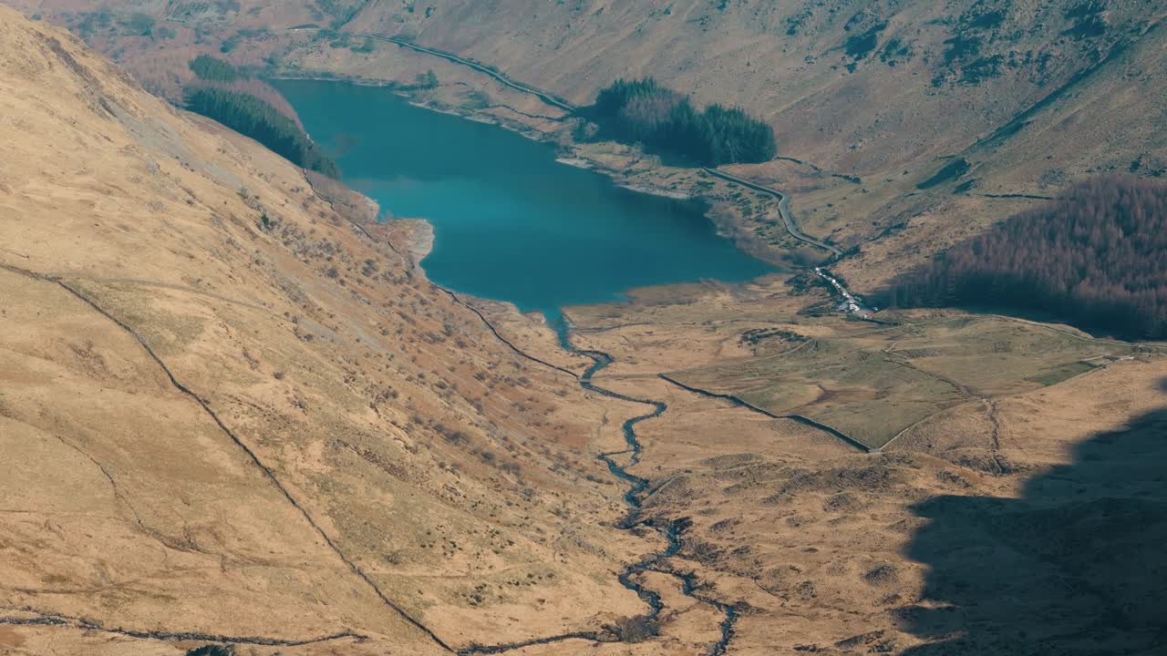 Aerial approach to large lake surrounded by forested hills in Lake District, England, panoramic establishing