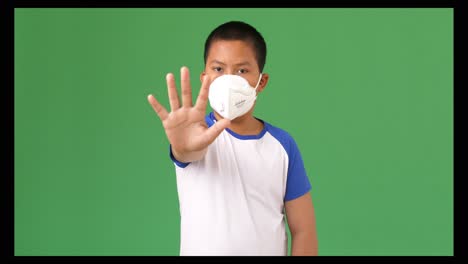 young boy in protective mask showing stop sign, green screen