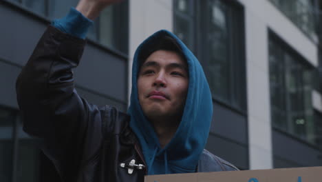 primer plano de un joven activista sosteniendo un cartel de cartón contra el uso de plástico durante una protesta contra el cambio climático