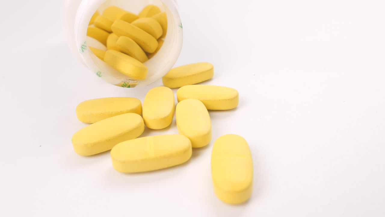 Close-up of Yellow Oval Pills Spilled from a Bottle