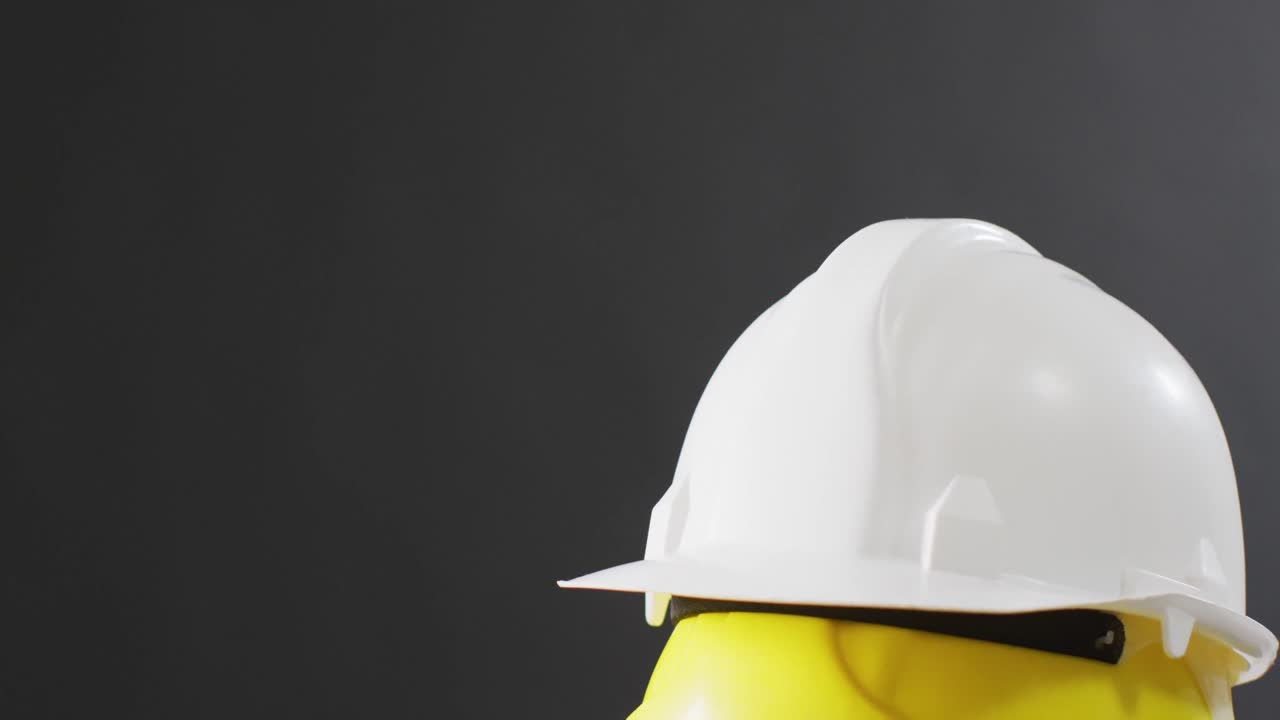 video de primer plano de coloridos cascos de construcción sobre un fondo gris