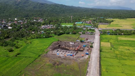 panoramic view of development construction side along provincial road and surrounding lush rice fields at malilipot, albay -aerial orbit shot