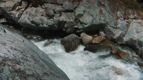 foamy water flowing through big rocks on the river in slow-motion