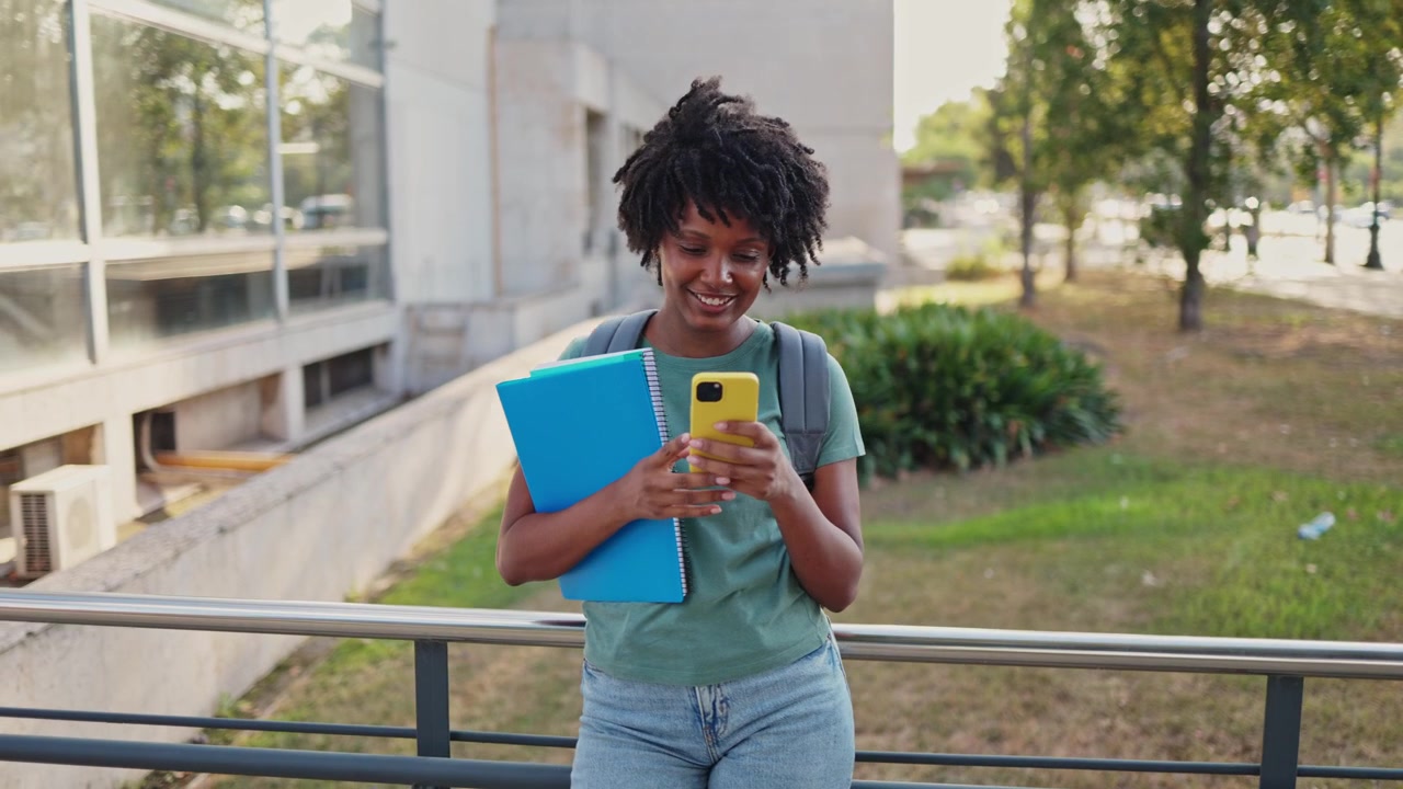 Happy Young Black Woman Student Using Smartphone Outdoors