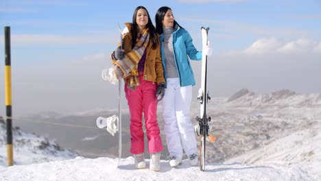 Two-female-snowboarders-standing-on-a-mountain