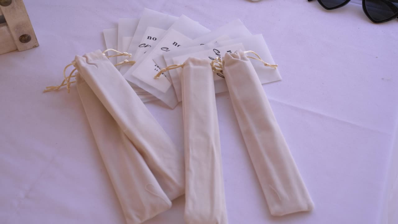 Colorful handmade pouches are arranged neatly on a table at a vibrant local market. Shoppers explore the unique designs and eco-friendly materials available for purchase