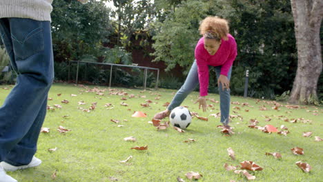 happy african american mother and son in scarf lying on fallen leaves in garden, slow motion