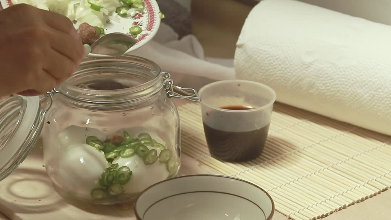 Adding spices and sugar to a mason jar containing hard-boiled eggs following a recipe of mayak gyeran or korean marinated egg, authentic traditional food from Korea