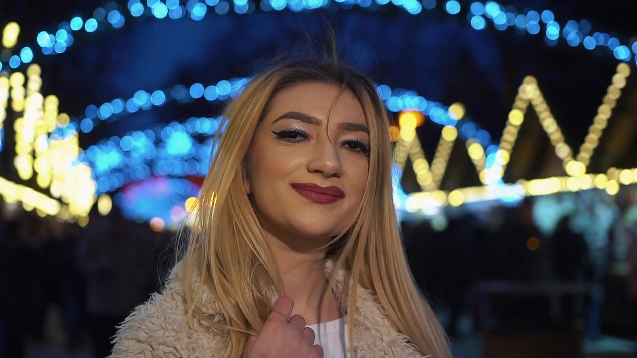 Giovane donna felice in posa con luci natalizie festive di notte