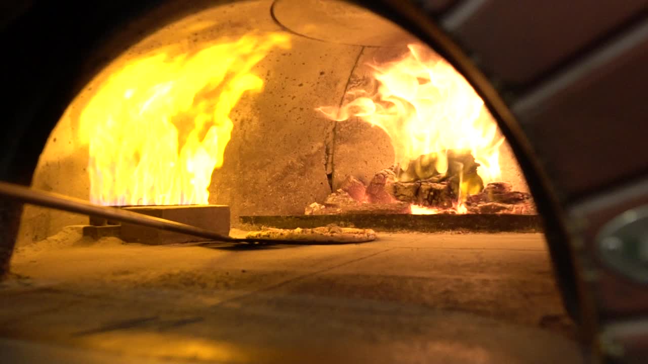 Pizzapohjan liikuttelu tiiliuunissa hidastettuna.